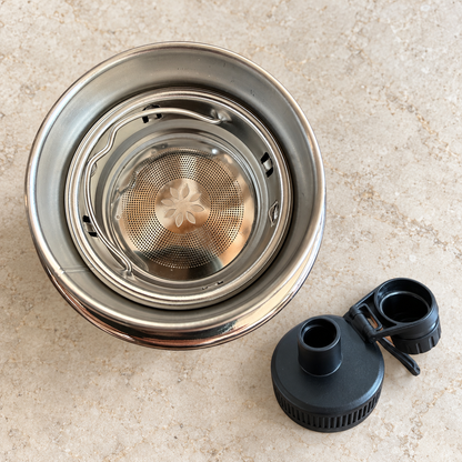 Overhead view of the fitted stainless steel infuser inside the bottle, with the drinking lid beside it
