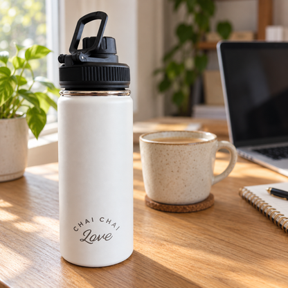 White Chai Chai Love insulated tea bottle on a desk beside a cup of chai and laptop; cup not included