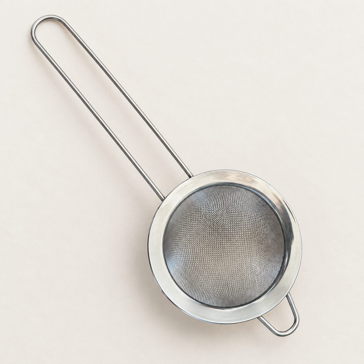 Overhead view of the round fine mesh chai strainer, long handle, and support loop